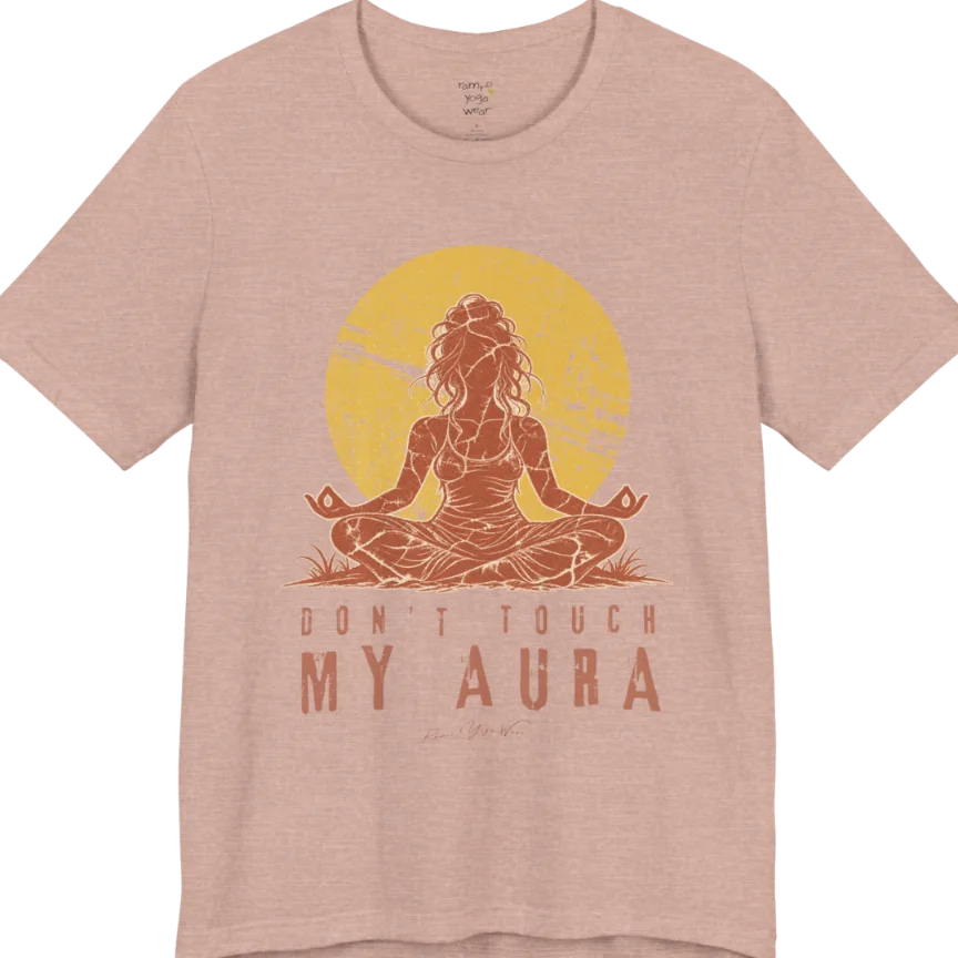 A short sleeved teed called the Aura T-Shirt, flat lay and a Bella + Canvas 3001 shirt. Simply says, Don't Touch My Aura. Design highlights a person meditating with a large bright sun in the background, all in a rustic, distressed illustration. Color is Heather Prism Peach.