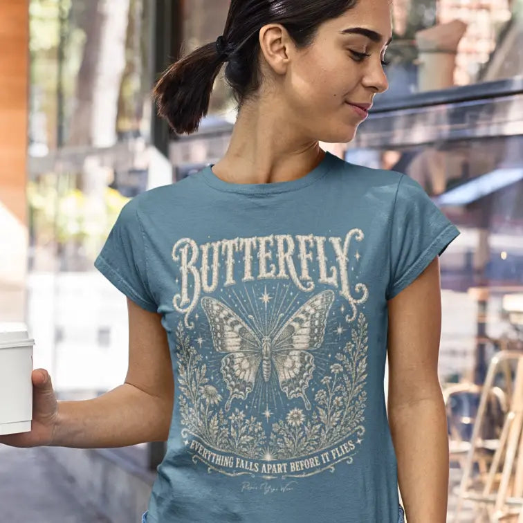 Woman wearing Butterfly T-Shirt outdoors on a city street, holding a coffee cup. Tee is Indigo Blue