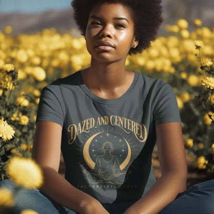 A person with curly hair sitting in a field of yellow flowers, wearing the Centered T-Shirt in Heather Navy with the Dazed and Centered design across the chest.