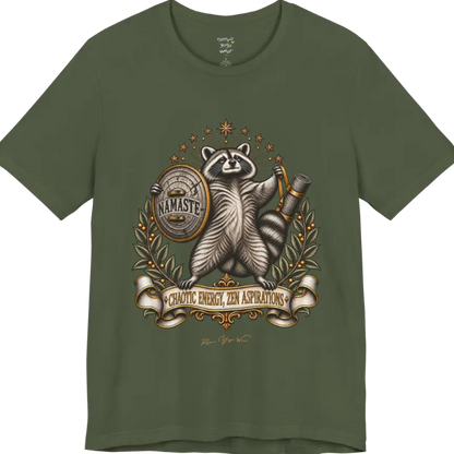 Illustrated raccoon crest holding a shield stamped "Namaste" and a rolled yoga mat, framed by stars and botanical laurel branches. Chaotic Zen T-Shirt flat lay is a Bella+Canvas 3001 and the color in Military Green.