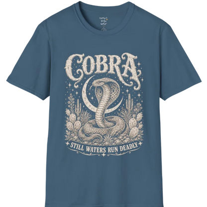 A grunge tee with an illustrated cobra design, hood flared, botanical linework framing the scene, text reading "Cobra" and "Still Waters Run Deadly" — Wild Animals collection by Ramro Yoga Wear in Indigo Blue.