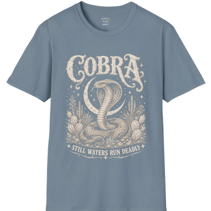 A grunge tee with an illustrated cobra design, hood flared, botanical linework framing the scene, text reading "Cobra" and "Still Waters Run Deadly" — Wild Animals collection by Ramro Yoga Wear in Stone Blue.