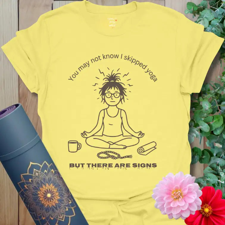 Cornsilk yellow Signs T-Shirt with hand-drawn yogi, mala beads, and coffee cup. Cheerful yoga-humor tee blending self-care and laughter.