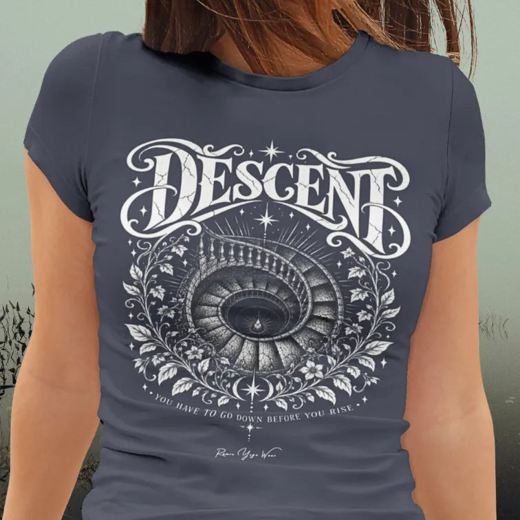 A woman sits in front of lagoon, wearing the Descent T-Shirt. Descent T-Shirt is a Gildan 64000, short sleeved tee and the color is Heather Navy.