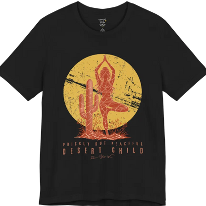 A short sleeved tee called the Desert Child T-Shirt, flat lay and a Bella + Canvas 3001 shirt. Simply says, Prickly But Peaceful, Desert Child. Design highlights a person in Tree Pose beside a desert cactus, with a large distressed sun in the background, in a rustic, distressed illustration. Color is Black.