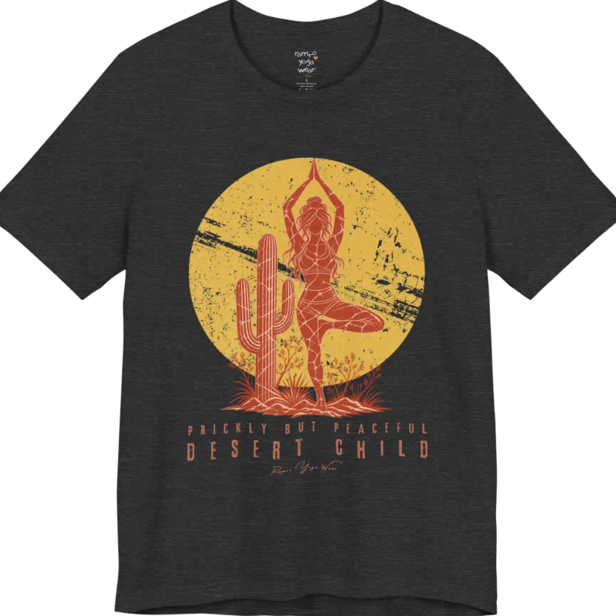 A short sleeved tee called the Desert Child T-Shirt, flat lay and a Bella + Canvas 3001 shirt. Simply says, Prickly But Peaceful, Desert Child. Design highlights a person in Tree Pose beside a desert cactus, with a large distressed sun in the background, in a rustic, distressed illustration. Color is Dark Grey Heather.
