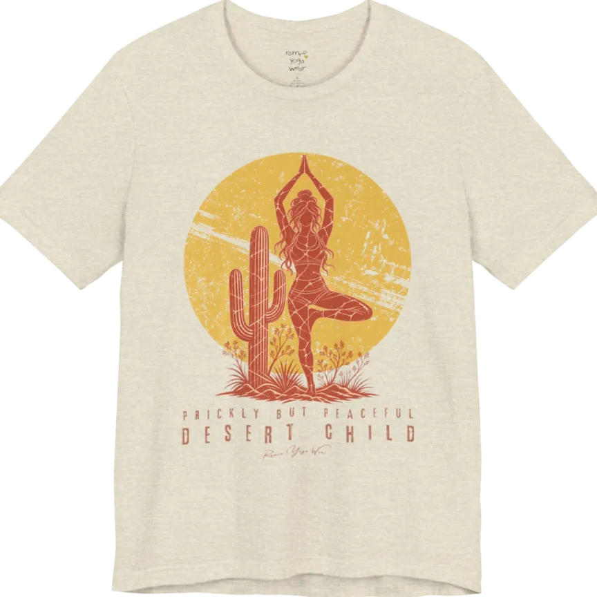 A short sleeved tee called the Desert Child T-Shirt, flat lay and a Bella + Canvas 3001 shirt. Simply says, Prickly But Peaceful, Desert Child. Design highlights a person in Tree Pose beside a desert cactus, with a large distressed sun in the background, in a rustic, distressed illustration. Color is Heather Prism Natural.