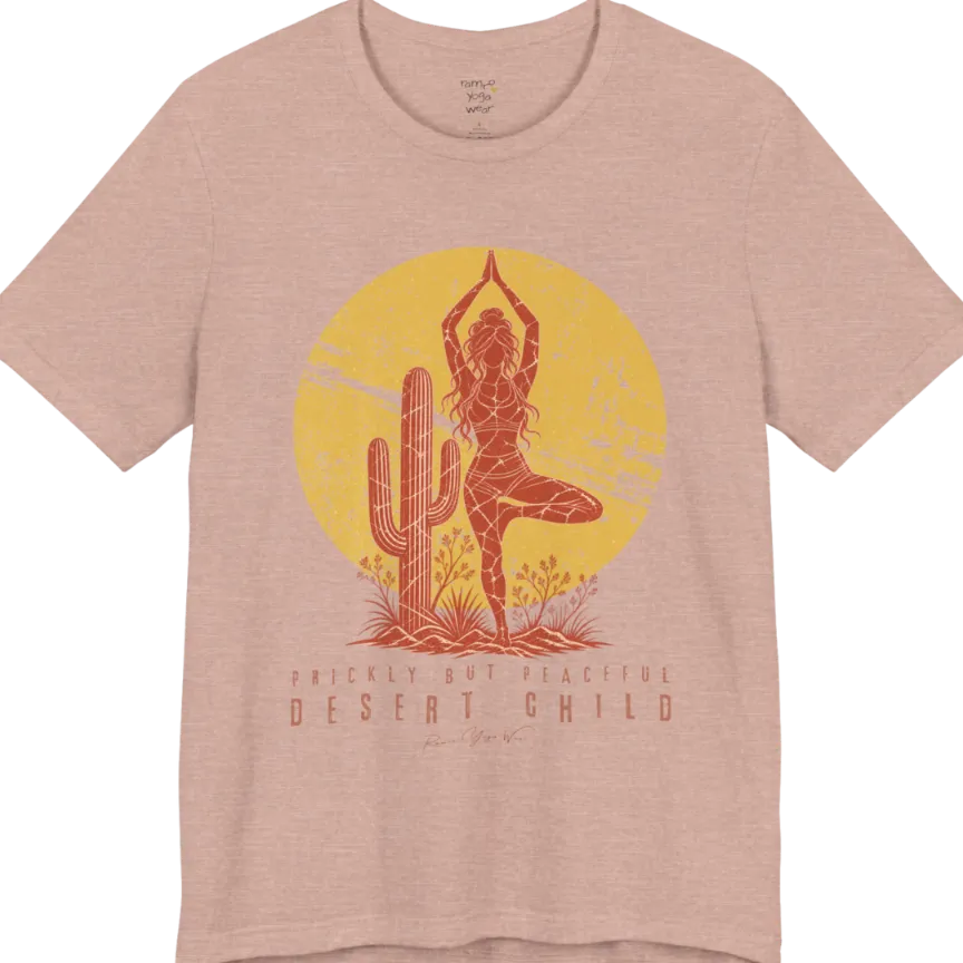 A short sleeved tee called the Desert Child T-Shirt, flat lay and a Bella + Canvas 3001 shirt. Simply says, Prickly But Peaceful, Desert Child. Design highlights a person in Tree Pose beside a desert cactus, with a large distressed sun in the background, in a rustic, distressed illustration. Color is Heather Prism Peach.