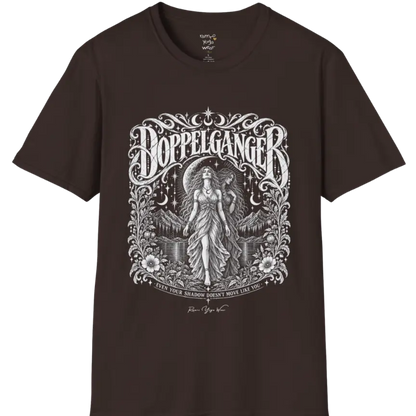 A short sleeved tee called the Doppelganger T-Shirt, flat lay and a Gildan 64000 shirt. Simply says, Even Your Shadow Doesn't Move Like You. Design highlights a woman standing before a crescent moon with a second shadow-self figure behind her, framed by mountains, florals, and ornate engraved linework border. Color is Dark Chocolate.