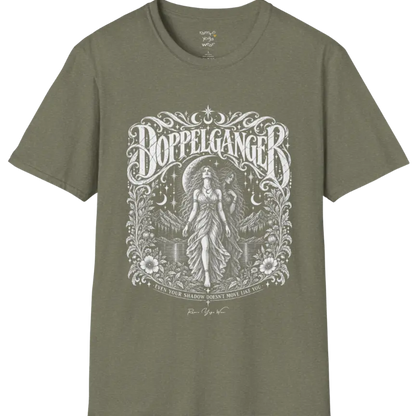 A short sleeved tee called the Doppelganger T-Shirt, flat lay and a Gildan 64000 shirt. Simply says, Even Your Shadow Doesn't Move Like You. Design highlights a woman standing before a crescent moon with a second shadow-self figure behind her, framed by mountains, florals, and ornate engraved linework border. Color is Heather Military Green.