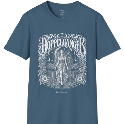 A short sleeved tee called the Doppelganger T-Shirt, flat lay and a Gildan 64000 shirt. Simply says, Even Your Shadow Doesn't Move Like You. Design highlights a woman standing before a crescent moon with a second shadow-self figure behind her, framed by mountains, florals, and ornate engraved linework border. Color is Indigo Blue.