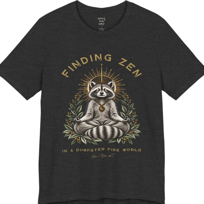 A short sleeved Tee of a meditating raccoon illustration with a gold sunburst halo and botanical leaf framing. Dumpster T-Shirt flat lay is a Bella+Canvas 3001 and the color is Dark Grey Heather.