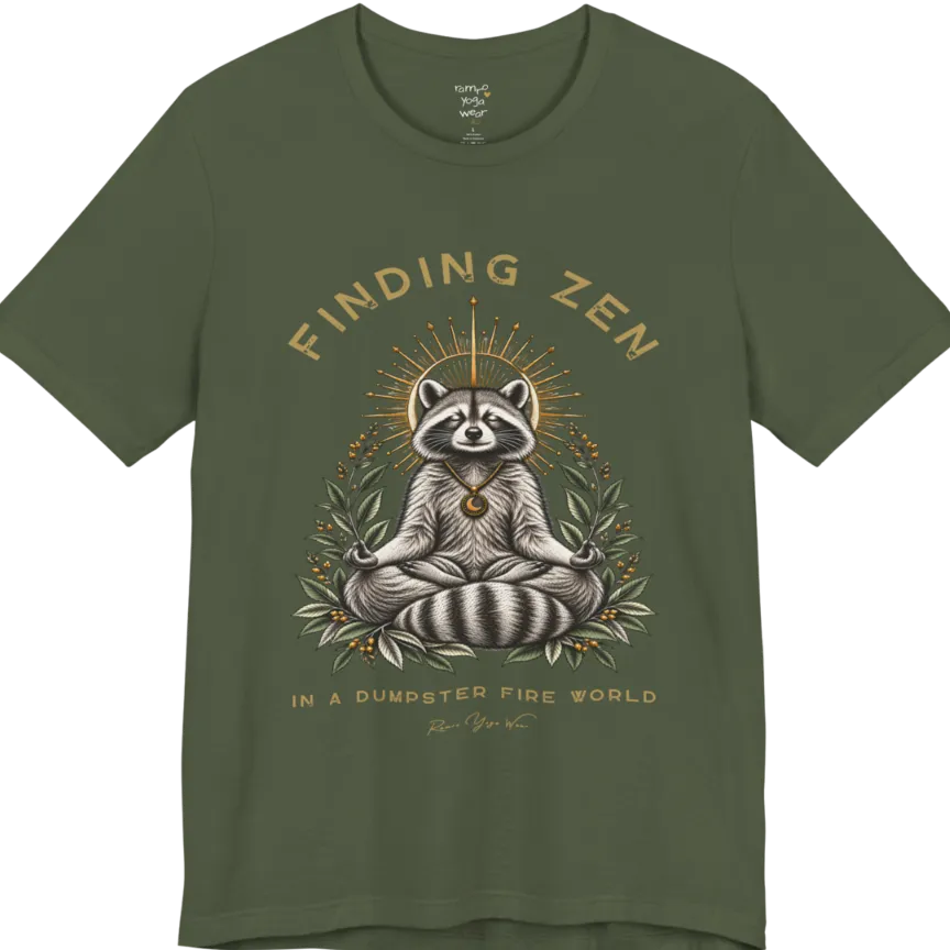 A short sleeved Tee of a meditating raccoon illustration with a gold sunburst halo and botanical leaf framing. Dumpster T-Shirt flat lay is a Bella+Canvas 3001 and the color is Military Green.