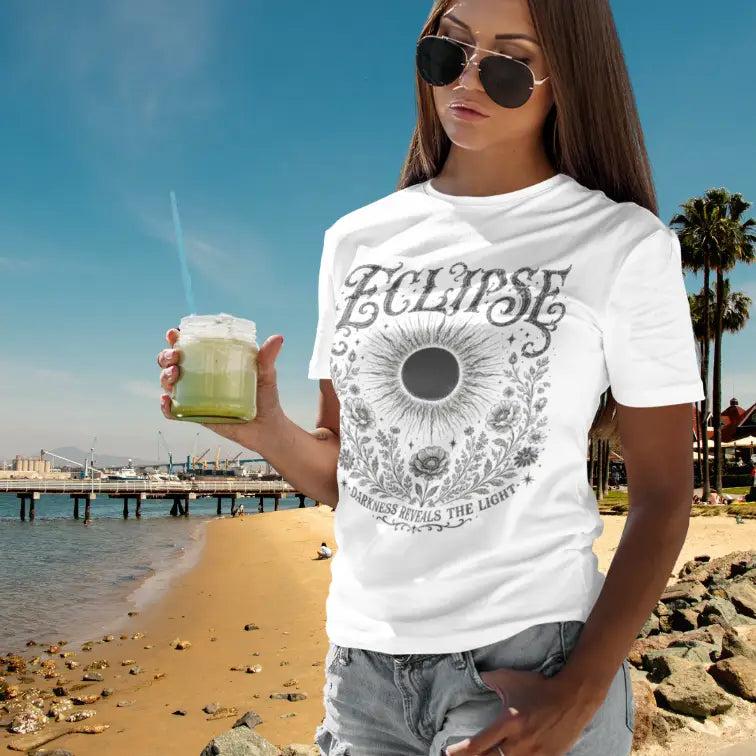 Lifestyle image of model wearing the white Eclipse T-Shirt on a sunny coastal boardwalk featuring celestial eclipse artwork and vintage mystical graphics.