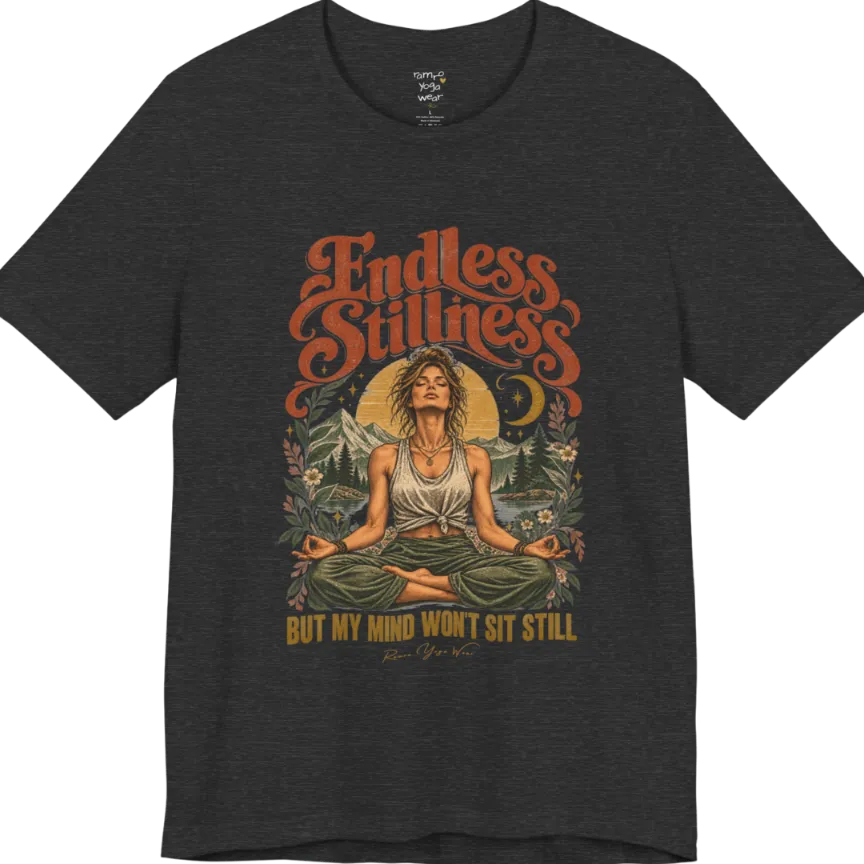 A short sleeved tee, showing an Illustration of a woman seated in lotus meditation pose in front of mountains, pine trees, and a crescent moon, framed by botanical leaves and flowers. Endless T-Shirt flat lay is a Bella+Canvas 3001 and the color is Dark Grey Heather.