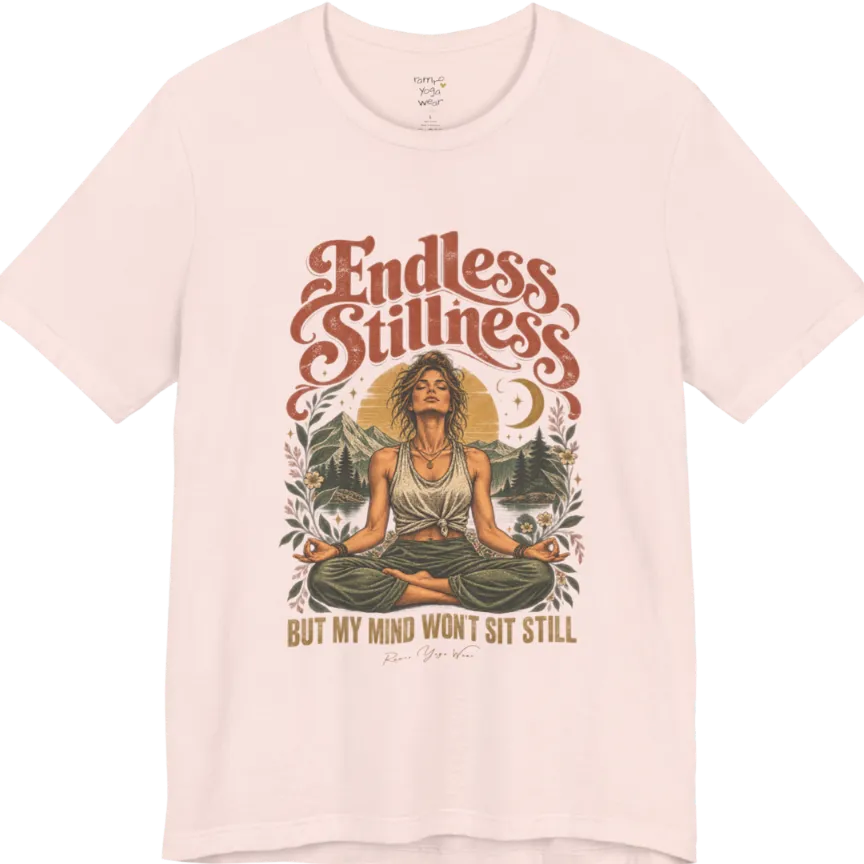 A short sleeved tee, showing an Illustration of a woman seated in lotus meditation pose in front of mountains, pine trees, and a crescent moon, framed by botanical leaves and flowers. Endless T-Shirt flat lay is a Bella+Canvas 3001 and the color is Soft Pink.
