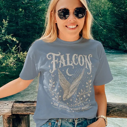 Person wearing the Falcon T-Shirt in Stone Blue, standing outdoors near a wooden fence with a river behind them — Wild Animals collection by Ramro Yoga Wear.