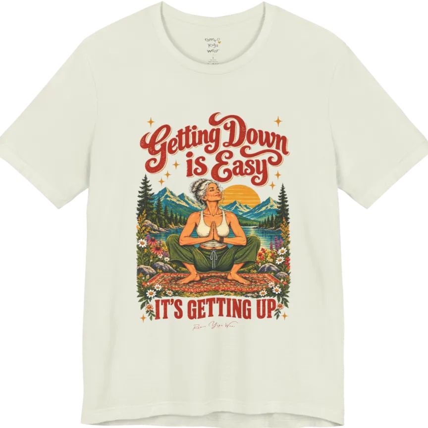 A short sleeved tee called the Getting Up T-Shirt, flat lay and a soft cotton blend shirt. Simply says, Getting Down is Easy, It's Getting Up. Design highlights retro red script lettering above a silver-haired person in a deep yoga squat with hands in prayer on a patterned mat, with a sun, mountains, a lake and wildflowers, bold red lettering for IT'S GETTING UP and a small script signature. Color is Citron.
