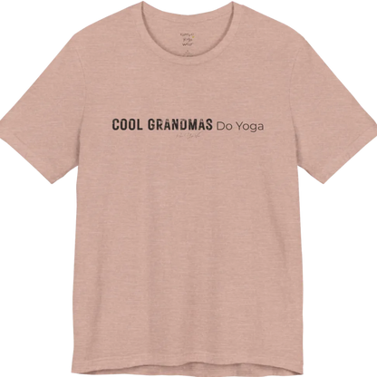 A short sleeved tee called the Grandmas T-Shirt, flat lay and a soft cotton blend shirt. Simply says, Cool Grandmas Do Yoga. Design highlights bold distressed block lettering for COOL GRANDMAS beside thin lettering for Do Yoga, with a small script signature underneath. Color is Heather Prism Peach.