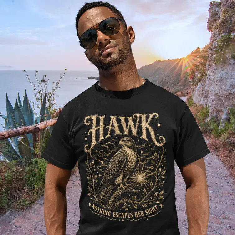 Person wearing Hawk black tee, standing on a coastal cliffside path at sunset — Wild Animals collection by Ramro Yoga Wear