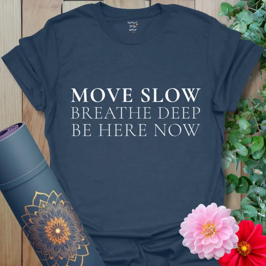 Heather Navy Be Here Now T-Shirt with three-line mindful message “Move Slow • Breathe Deep • Be Here Now” in white serif text. Soft unisex yoga shirt for calm, grounding style.