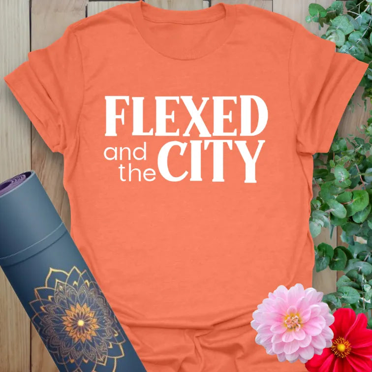 Vibrant orange yoga t-shirt showcasing strong and stylish "Flexed and the City" text for active lifestyle lovers.