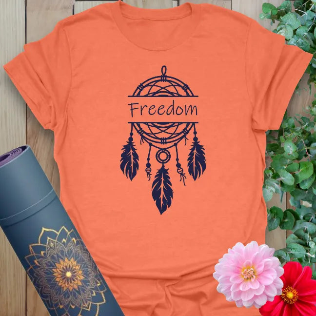 Vibrant orange yoga t-shirt showcasing dreamcatcher and feather design inspiring freedom, hope, and conscious movement.