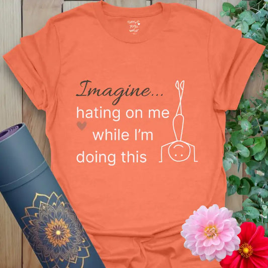Heather Orange Imagine T-Shirt with white text reading “Imagine hating on me while I’m doing this.” Minimalist headstand figure with Ramro heart accent — yoga humor meets balance and calm.