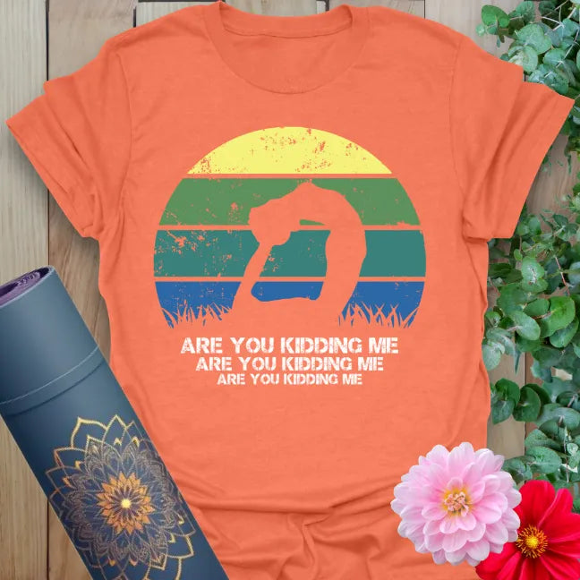Vibrant orange yoga t-shirt showcasing humorous yogi silhouette and retro "Are You Kidding Me" message for mindful humor.