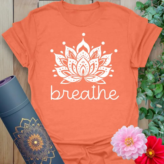 Vibrant orange yoga t-shirt showcasing detailed lotus and "breathe" design inspiring calm, soulful presence.