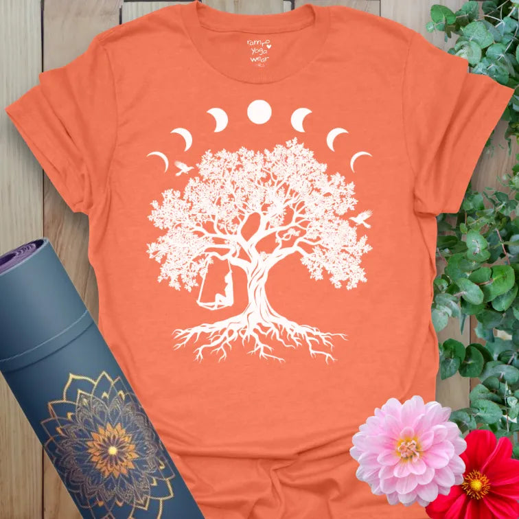 Vibrant orange yoga t-shirt showcasing sacred tree, moon phases, and whimsical swing design inspiring soulful freedom and conscious connection.