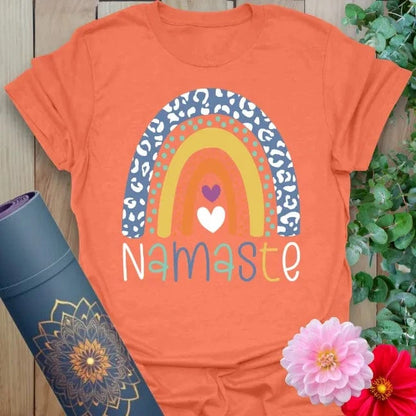 Vibrant orange yoga t-shirt showcasing whimsical rainbow design and heartfelt Namaste message for soulful positivity.
