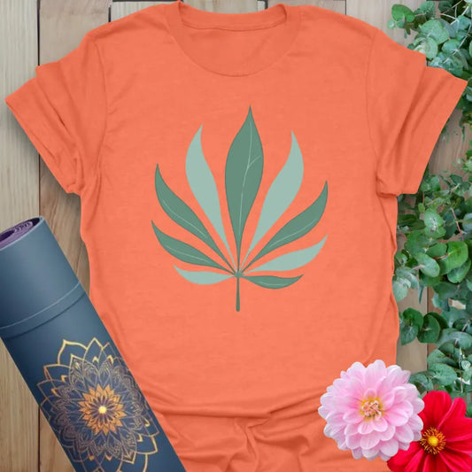 Vibrant orange yoga t-shirt showcasing stylized palm leaf artwork for grounded, soulful, earth-connected living.