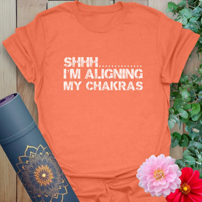 Vibrant orange yoga t-shirt showcasing funny chakra alignment message inspiring peaceful, conscious movement.