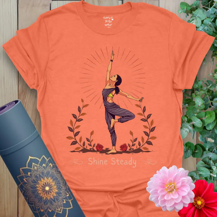 Vibrant orange yoga t-shirt showcasing “Shine Steady” yogi artwork inspiring empowered, conscious movement and rooted strength.