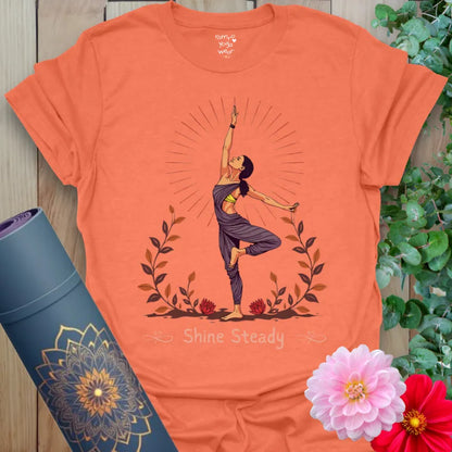 Vibrant orange yoga t-shirt showcasing “Shine Steady” yogi artwork inspiring empowered, conscious movement and rooted strength.