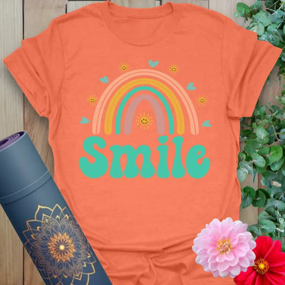 Vibrant orange yoga t-shirt showcasing cheerful rainbow and playful "Smile" design promoting positivity and mindful happiness.