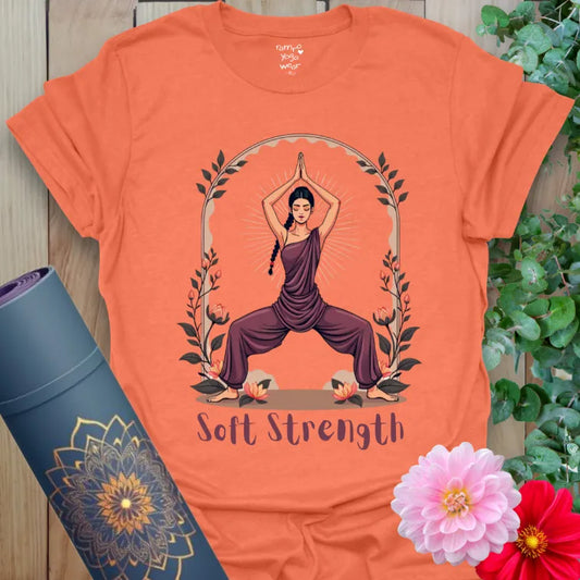 Vibrant orange yoga t-shirt showcasing powerful Goddess Pose design and “Soft Strength” quote for feminine energy and grounded movement.