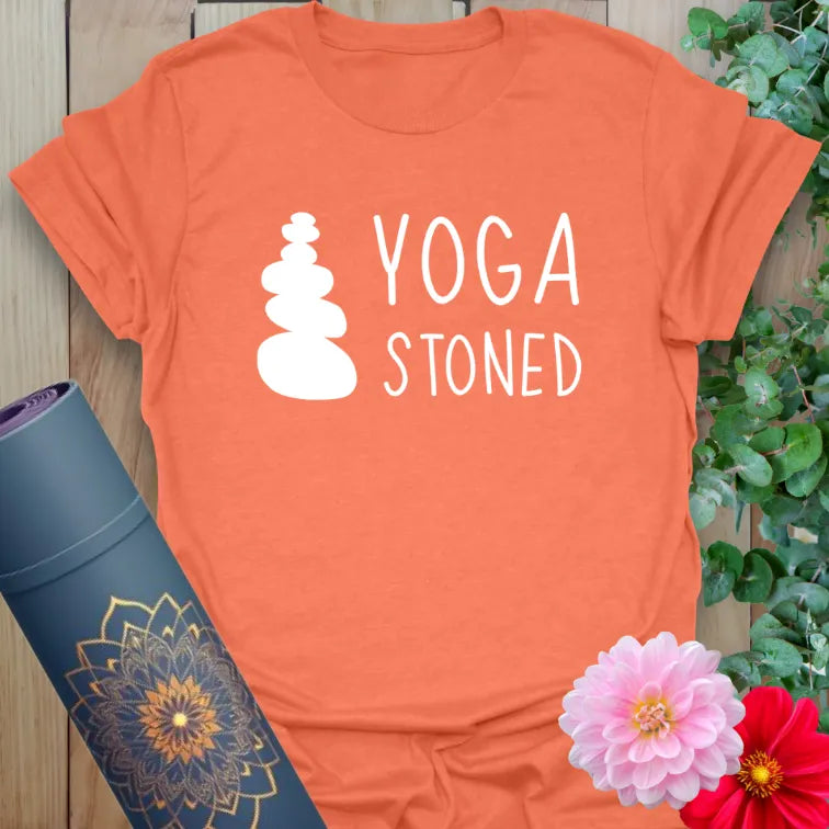 Vibrant orange yoga tee with playful “YOGA STONED” phrase and minimalist stone stack for conscious comedy.