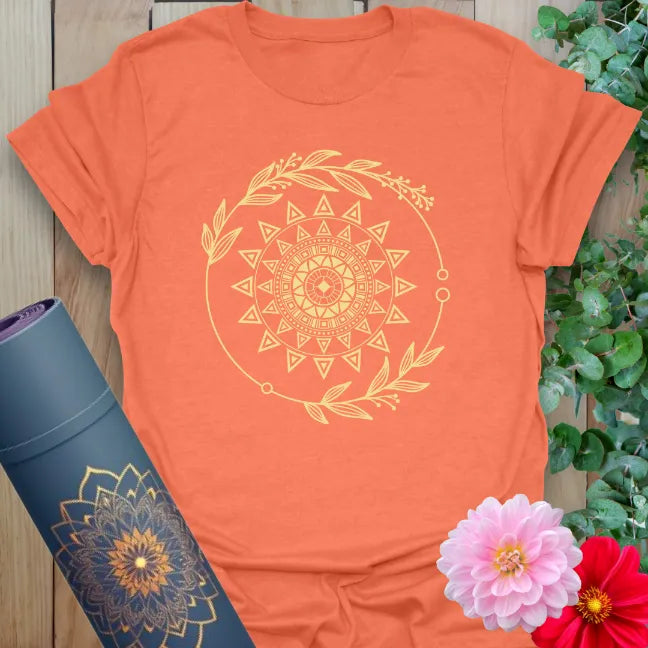 Vibrant orange t-shirt with celestial sacred sun design and botanical accents for conscious, empowered wear.