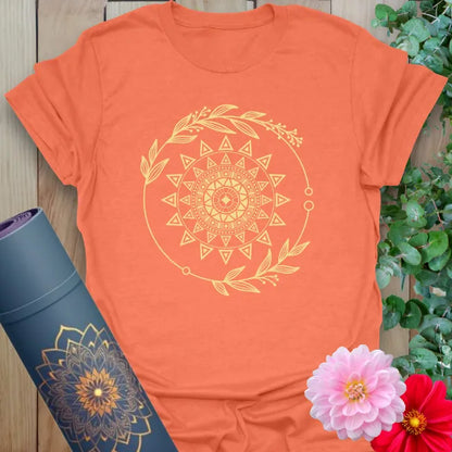 Vibrant orange t-shirt with celestial sacred sun design and botanical accents for conscious, empowered wear.
