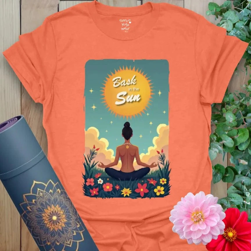 Vibrant orange t-shirt featuring sunrise meditation scene and blooming florals with inspirational message for joyful yoga wear.