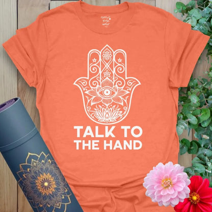 Vibrant orange t-shirt featuring white Hamsa graphic and cheeky yoga mantra for conscious, comedic wear.