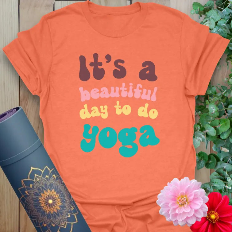 Vibrant orange t-shirt with colorful motivational yoga quote for playful, conscious movement lovers.
