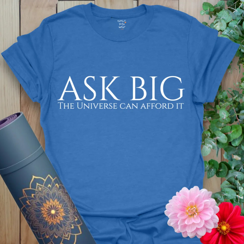 Deep heather royal yoga tee with “Ask Big — The Universe Can Afford It” design for bold manifestation and mindful wear.