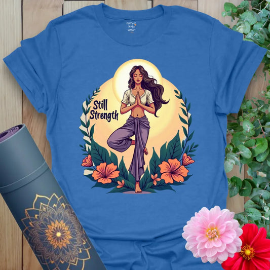Soft cotton yoga tee featuring goddess yogi in Tree Pose with floral backdrop and “Still Strength” message, radiating power and peace.