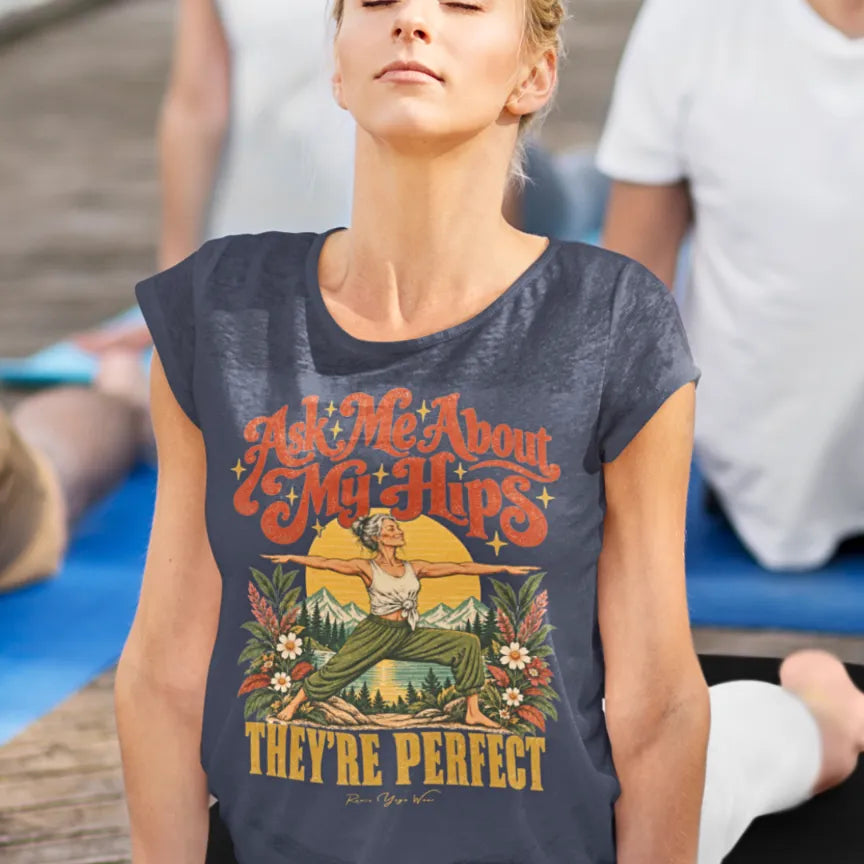 A woman in Cobra Pose outdoors in her yoga class, wearing a Heather Midnight Navy Hips T-Shirt with a retro illustration of a woman in warrior two pose.
