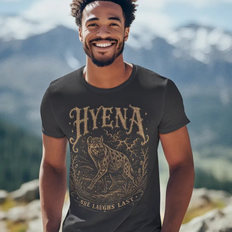 Man wearing Hyena T-Shirt outdoors with mountains behind him, smiling, shirt in Dark Heather Grey.