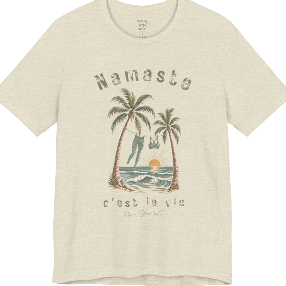 A short sleeved grunge tee with an illustrated scene of two palm trees framing a clothesline with leggings and a sports bra hanging between them, sun setting over waves, text reading "Namaste" and "c'est la vie" — Funny Yoga Shirts collection by Ramro Yoga Wear in 