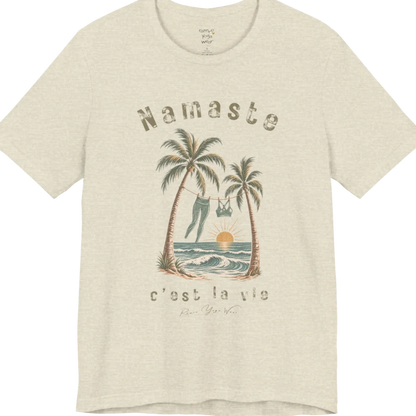 A short sleeved grunge tee with an illustrated scene of two palm trees framing a clothesline with leggings and a sports bra hanging between them, sun setting over waves, text reading "Namaste" and "c'est la vie" — Funny Yoga Shirts collection by Ramro Yoga Wear in 